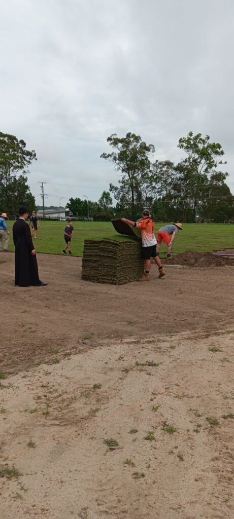 Volunteers laying turf at the new Holy Cross FC home ground